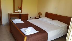 1 dormitorio con 1 cama con toallas en Lazaros Pissouri Apartments, en Pissouri