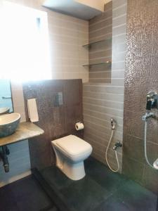 a bathroom with a toilet and a sink and a shower at Tatvam Residency in Kolkata