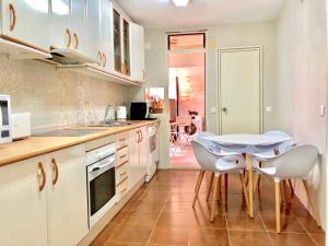 アリカンテにあるApartment Grand Fernando Explanada Alicanteの白いキャビネット、テーブルと椅子付きのキッチンが備わります。