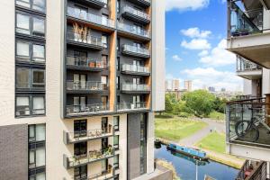 ロンドンにあるBeautiful, Secure, 2-bedroom Canal-side Apartmentのバルコニーと川が備わるアパートメントビル