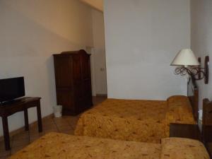 a hotel room with a bed and a couch and a tv at Hotel Antiguo Fortin in Oaxaca City