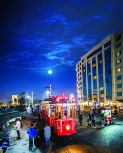 a red trolley car on a city street at night at Taksim Square Hotel in Istanbul