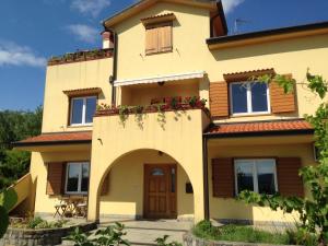 a large yellow house with a balcony with red flowers at Apartma Valmarin in Spodnje Škofije