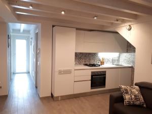 a kitchen with white cabinets and a living room at Casadina in Monte Isola