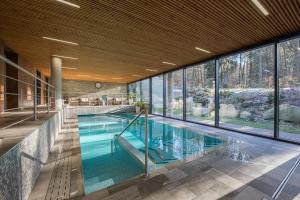 an indoor swimming pool with a large glass wall at Wellness & Spa hotel Villa Regenhart in Jeseník
