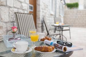 a table with a breakfast of croissants and orange juice at Luxury Rooms Saint Jacob in Trogir