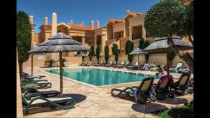 a resort with a swimming pool with lawn chairs and umbrellas at Luz Beach Luxury Apartment in Luz