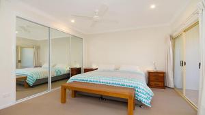 a bedroom with a bed and a bench and a mirror at Orient Lane on the Hill by Kingscliff Accommodation in Kingscliff