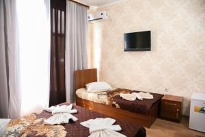 a hotel room with two beds and a tv on the wall at Bon Amour in Gagra