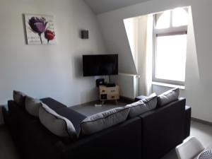salon z czarną kanapą i telewizorem w obiekcie Discover w mieście Ypres