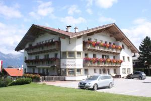 a large white building with flowers in a parking lot at Pension Sonnenheim in Schönberg im Stubaital