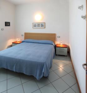 1 dormitorio con 1 cama azul y 2 mesitas de noche en Residence Torre di Noe, en Bibione