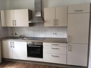 a kitchen with white cabinets and a sink and a stove at Familien-Ferienwohnung Fiwa FeWo-3 in Pirmasens