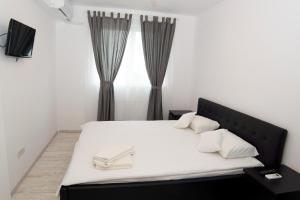 a white bed with a white comforter and pillows at Denisa Apartamente in Otopeni