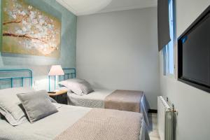 a bedroom with two beds and a flat screen tv at Serrano Comfort, by Presidence Rentals in Madrid