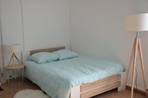 een slaapkamer met een bed met een blauw dekbed en 2 lampen bij Joli Studio Plein Centre de Milly la Forêt in Milly-la-Forêt