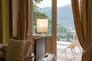 uma sala de estar com uma televisão e uma janela em Hotel & Terme Bagni di Lucca em Bagni di Lucca