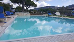 una gran piscina con sillas azules y una mesa en La Locanda della Vecchia Hosteria, en Gavorrano