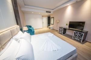 a hotel room with a white bed and a flat screen tv at Sole Luna Hotel in Borsh