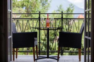 a table with two wine glasses and a bottle on a balcony at Design & Wine Vila Special Bled in Bled