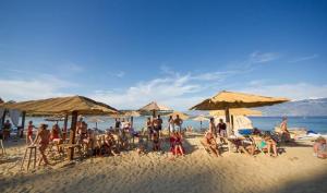 a group of people sitting on a beach with umbrellas at Apartments Banic in Rab