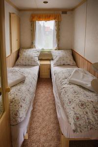 2 łóżka w małym pokoju z oknem w obiekcie Domek angielski w Białowieży