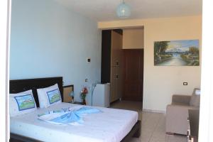 een slaapkamer met een groot wit bed met blauwe kussens bij Hotel Aleksandrus Jardin in Durrës