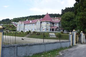 una casa grande con una valla delante en Nirvana Retreat en Kurseong