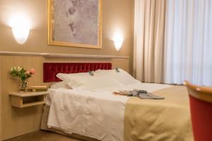 une chambre d'hôtel avec un lit avec une tête de lit rouge dans l'établissement Santa Barbara Hotel, à San Donato Milanese