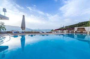 a large swimming pool with an umbrella and chairs at Princess Kyniska Suites in Plitra