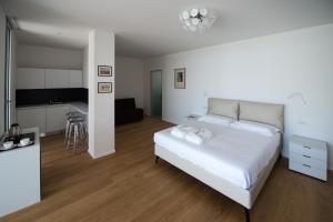 1 dormitorio con 1 cama blanca y cocina en B&B Capo Torre Resort & SPA, en Albisola Superiore