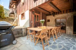 a wooden table and chairs on a patio with a grill at Chalet Vogue in Morzine