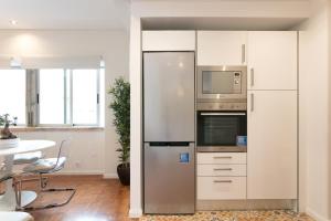 Il comprend une cuisine équipée d'un réfrigérateur en acier inoxydable et d'une table. dans l'établissement Your Lisbon Home - Duque de Palmela, à Lisbonne