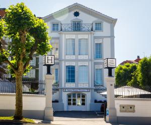 a white house with a tree in front of it at Suite Home Pinares in Santander