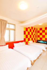 two beds in a room with a checkered wall at Happiness B&B in Magong