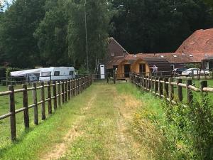 een boerderij met een hek en een trailer en een gebouw bij De Rozephoeve Studio in Oisterwijk