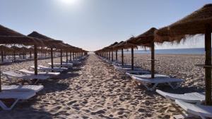 uma fila de cadeiras e guarda-sóis numa praia em Praia Verde Villa em Altura