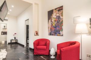 una sala de estar con 2 sillas rojas y una pintura en Shalai Relais Apartment, en Pachino