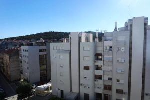 a tall white building with a mountain in the background at Apartman Tedi in Split