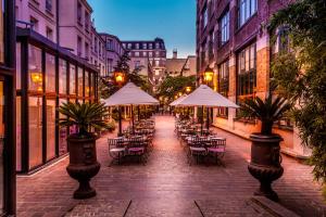 una calle vacía con mesas, sillas y sombrillas en Les Jardins Du Marais, en París