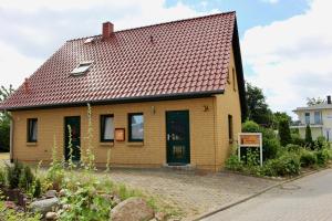 een klein geel huis met een rood dak bij Ferienhaus Zum Findling in Göhren