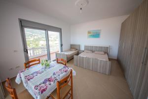 1 dormitorio con mesa, 1 cama y balcón en Himara Apartments, en Himare