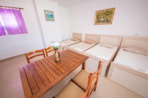 a room with a table and chairs and two beds at Himara Apartments in Himare