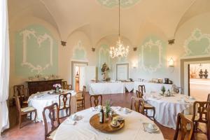 ein Esszimmer mit Tischen, Stühlen und einem Kronleuchter in der Unterkunft Badia a Coltibuono Wine Resort in Gaiole in Chianti