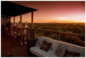 a couch on a deck with a view of the desert at Thali Thali Game Lodge in Langebaan