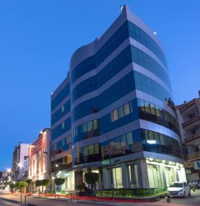 een hoog glazen gebouw met een auto voor het gebouw bij Hôtel Sidi Yahia in Alger