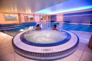 un hombre y una mujer en un jacuzzi en una piscina en Hillgrove Hotel, Leisure & Spa en Monaghan