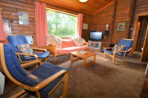 a living room with chairs and a couch and a tv at 18 Lamont Lodges in Dunoon