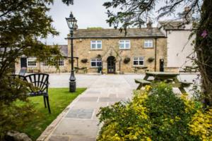 ein Gebäude mit einer Bank und einem Tisch davor in der Unterkunft The Sawley Arms in Ripon