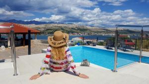 uma pessoa com um chapéu sentado ao lado de uma piscina em Apartments Ivita em Pag